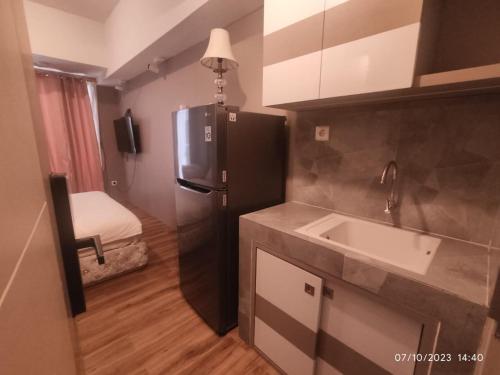 a kitchen with a black refrigerator and a sink at Apartemen Tokyo Riverside PIK2 tower Chikusei 