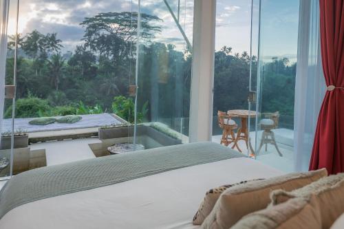 a bedroom with a bed and a large glass window at Villa Cella Bella Ubud in Ubud