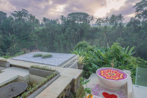a balcony with a bed and a bowl of flowers at Villa Cella Bella Ubud in Ubud