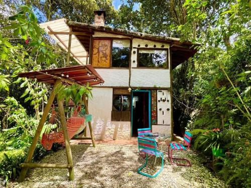 una casa con sillas y un columpio delante de ella en El bosque de las hadas II (Cabaña Magic House) en Santa Elena