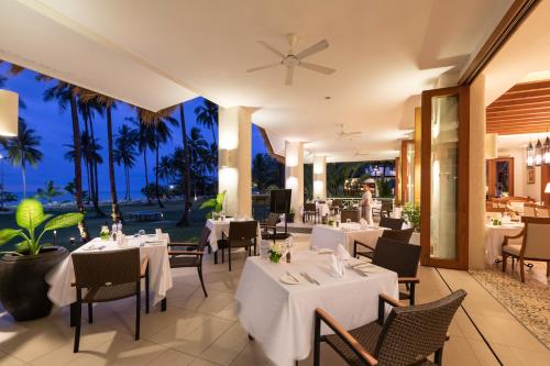 a restaurant with white tables and chairs and palm trees at Kantary Beach Hotel Villas & Suites in Khao Lak