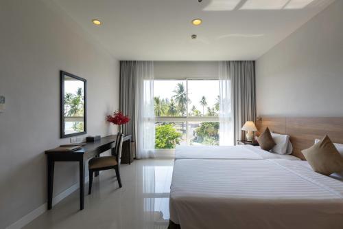 a hotel room with two beds and a desk and a window at Kantary Beach Hotel Villas & Suites in Khao Lak