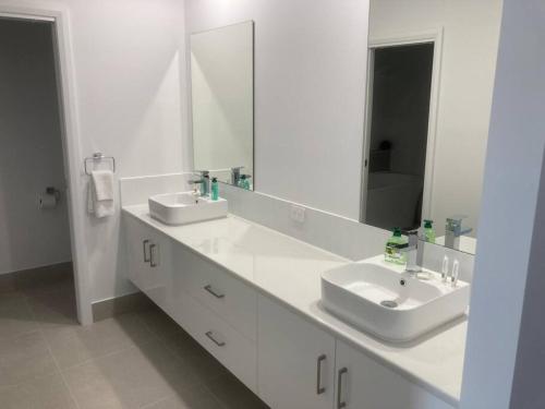a white bathroom with two sinks and a mirror at Kincaid@234 in Wagga Wagga