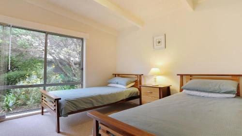 - 2 lits dans une chambre avec une grande fenêtre dans l'établissement Paradise Court 6, Tura Beach, à Tura Beach