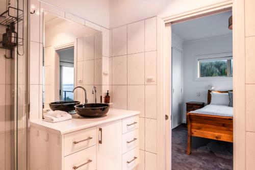 a bathroom with two sinks and a mirror at Ensorcelled - Freycinet Holiday Houses in Swansea