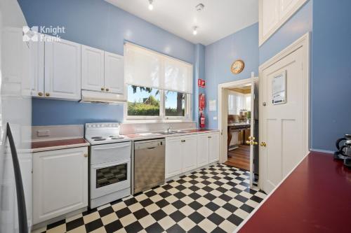eine Küche mit weißen Schränken und einem karierten Boden in der Unterkunft Clydesdale Manor in Hobart