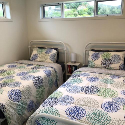 - une chambre avec 2 lits et 2 fenêtres dans l'établissement Hosts on the Coast Sea Blue Hideaway, à Kuaotunu