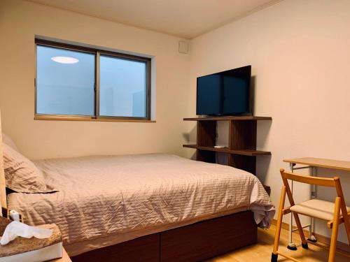 1 dormitorio con 1 cama y TV de pantalla plana en K.House en Tokio