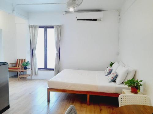 a white bedroom with a bed and a large window at Baan 192 in Bangkok