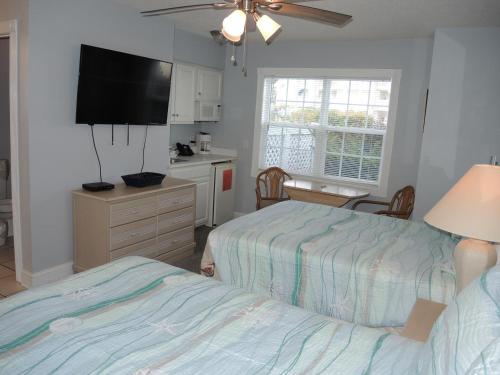 a bedroom with two beds and a kitchen with a tv at Studio Home 1203L at Brunswick Plantation Resort and Golf Villas in the Heart of NC Seafood Country studio in Calabash
