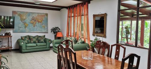 a dining room with a table and a green couch at Casa Kibi Kibi in San José