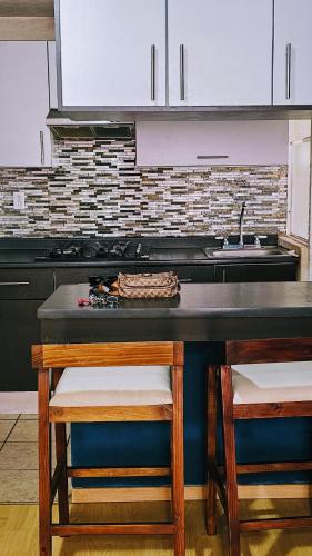 a kitchen with a sink and a table with stools at Departamento vergel Morelia in Morelia