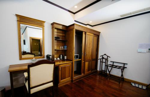 a room with a desk and a chair and a mirror at Sisombat Plaza Hotel in Vang Vieng