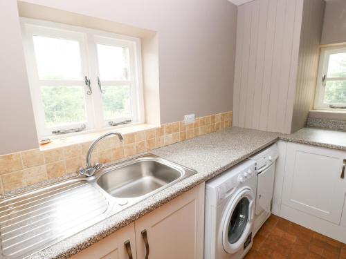 cocina con fregadero y lavadora en Gwyddno Lodge, en Narberth