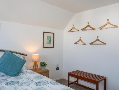 a bedroom with a bed and a table and hangers at Crows Nest - Rhosneigr in Rhosneigr