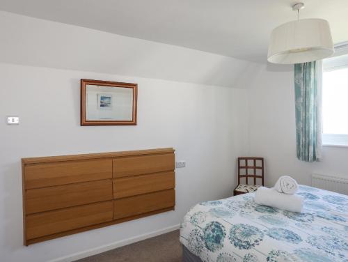 a bedroom with a dresser and a bed at Crows Nest - Rhosneigr in Rhosneigr
