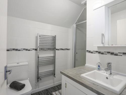 a white bathroom with a sink and a shower at Crows Nest - Rhosneigr in Rhosneigr