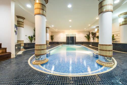 a swimming pool in a building with columns at Hotel Florença in Talatona