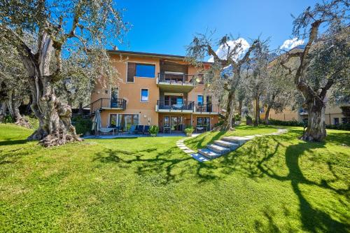 a building with trees in front of a yard at CallaLillyJardin in Malcesine