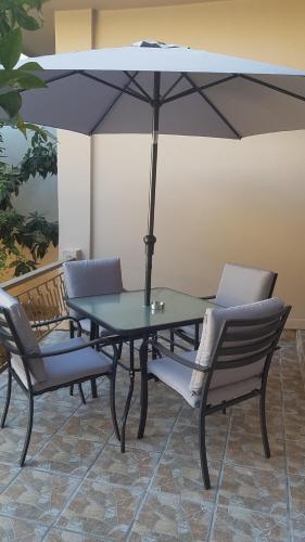 uma mesa e cadeiras com um guarda-sol num pátio em Katerina Holiday House em Anavissos