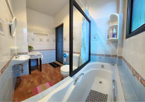 a bathroom with a tub and a sink and a toilet at The Sun House in Hua Hin