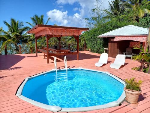 a swimming pool on a deck with a gazebo at Pension LE PASSAGE vue jardin in Vaitoare