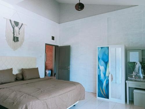 a bedroom with a bed and a painting on the wall at Villa Forest Puncak in Tagalbato