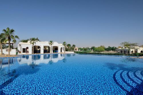 a large swimming pool in a resort with palm trees at InterContinental Durrat Al Riyadh Resort & Spa by IHG in Riyadh