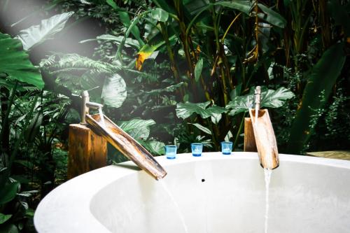 eine Badewanne mit zwei Wasserhähnen und zwei Trinkgläsern in der Unterkunft Proud Phu Fah Hip & Green Resort in Mae Rim