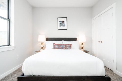 a white bedroom with a large bed and two lamps at CozySuites Music Row Elegant 1BR w free parking 51 in Nashville