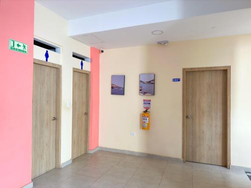 a hallway with two doors and a pink wall at Hotel Zamay Centro Historico in Santa Marta
