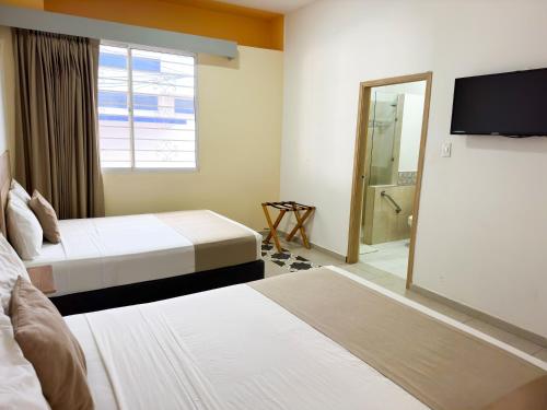 a hotel room with two beds and a television at Hotel Zamay Centro Historico in Santa Marta