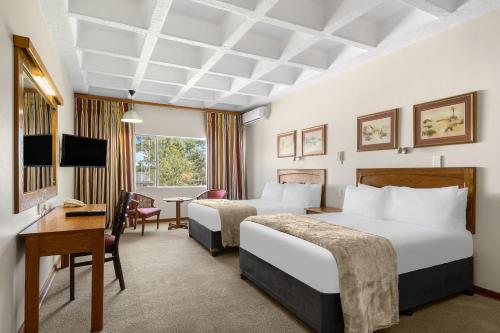 a hotel room with two beds and a desk at Park Hotel Mokopane in Mokopane