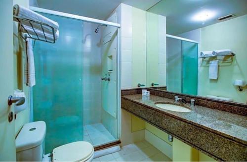 uma casa de banho com uma cabina de duche em vidro, um WC e um lavatório. em Nobile Congonhas em São Paulo