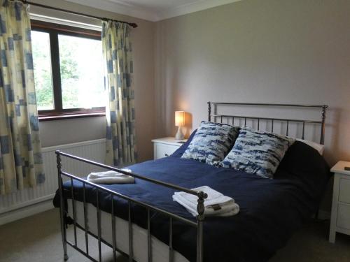 a bedroom with a bed with blue sheets and a window at Red Tree Cottage in York