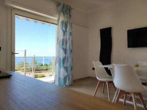 ein Wohnzimmer mit einem Tisch und Stühlen sowie einem großen Fenster in der Unterkunft Stefanelli Tropea Home in Tropea