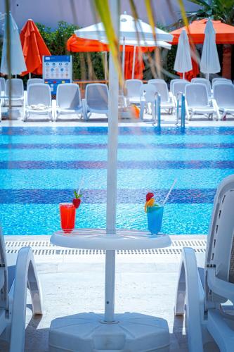 a swimming pool with chairs and a table with drinks at Oz Hotels Sui in Alanya