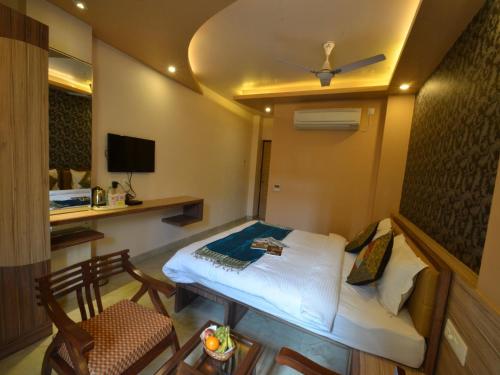 a room with a bed and a chair and a tv at Hotel Banaras Haveli in Varanasi