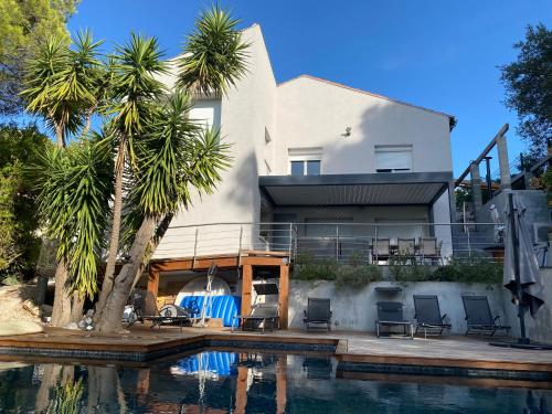 une maison avec une piscine et des palmiers dans l'établissement Bas de villa avec piscine, 5km de la plage, à La Seyne-sur-Mer