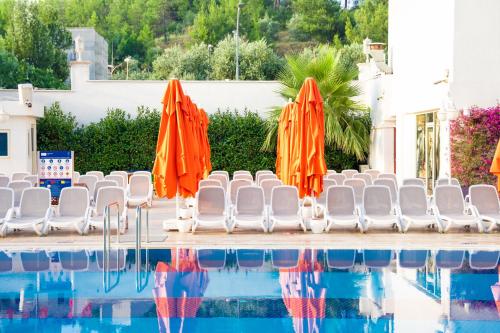 a group of orange umbrellas and chairs next to a swimming pool at Oz Hotels Sui in Alanya