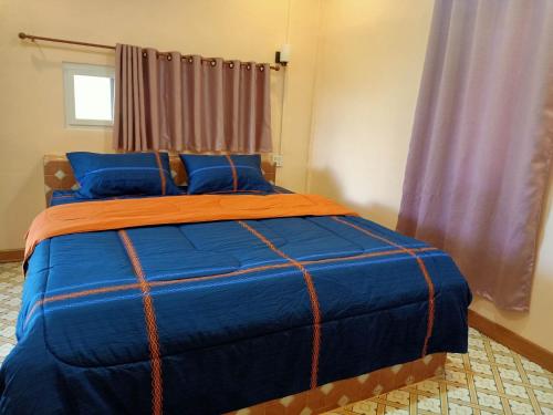 uma cama com um edredão laranja e azul num quarto em วรรณรีสอร์ทwanresort em Seka
