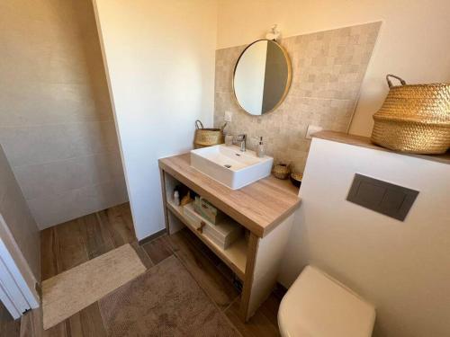 une salle de bain avec un lavabo et un miroir dans l'établissement Maison neuve proche de l'Océan et au calme, à Mimizan