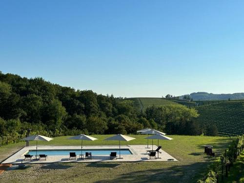 una piscina con sombrillas, mesas y sillas en Bosco Romagno, en Cividale del Friuli