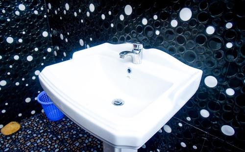 ein weißes Waschbecken im Bad mit einer schwarzen Wand in der Unterkunft Eco Diamond Palace in Ella