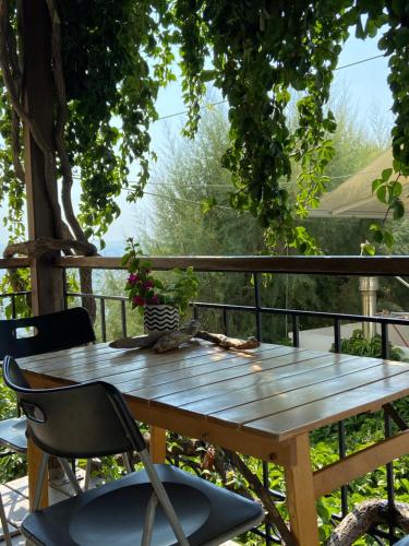 una mesa de madera y sillas en una terraza con un árbol en Pinelopi Holiday House, en Melínta
