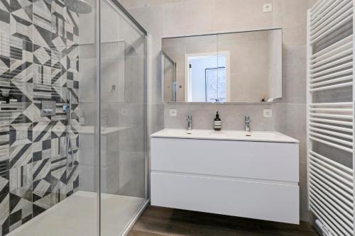 a white bathroom with a sink and a shower at Luxe-appartement aan de Schelde in Antwerp