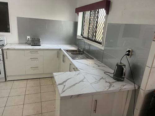 a white kitchen with a sink and a counter at Tonga Holiday Villa in Nuku‘alofa