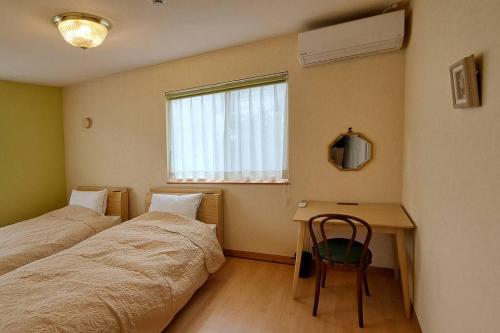 una camera con 2 letti, una scrivania e una finestra di ホリデーハウス慈野(ジノ) a Takayama