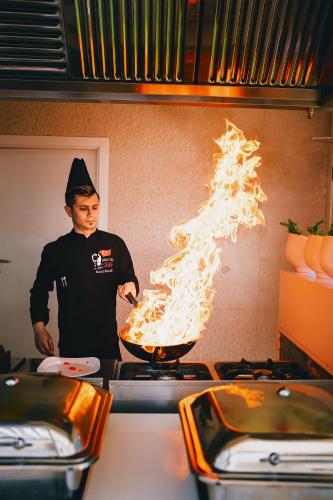 a man cooking food in a pan on a stove at Oz Hotels Sui in Alanya