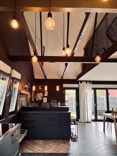 a large kitchen with black cabinets and lights at Villa - Stilvolles Boutique Landhaus in Grömitz